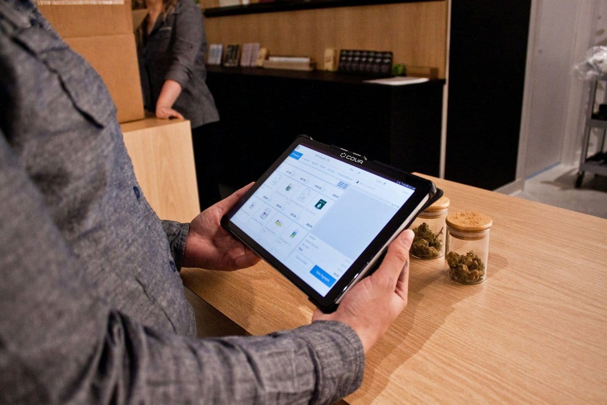 Ondernemer met een tablet-app achter de balie van zijn winkel