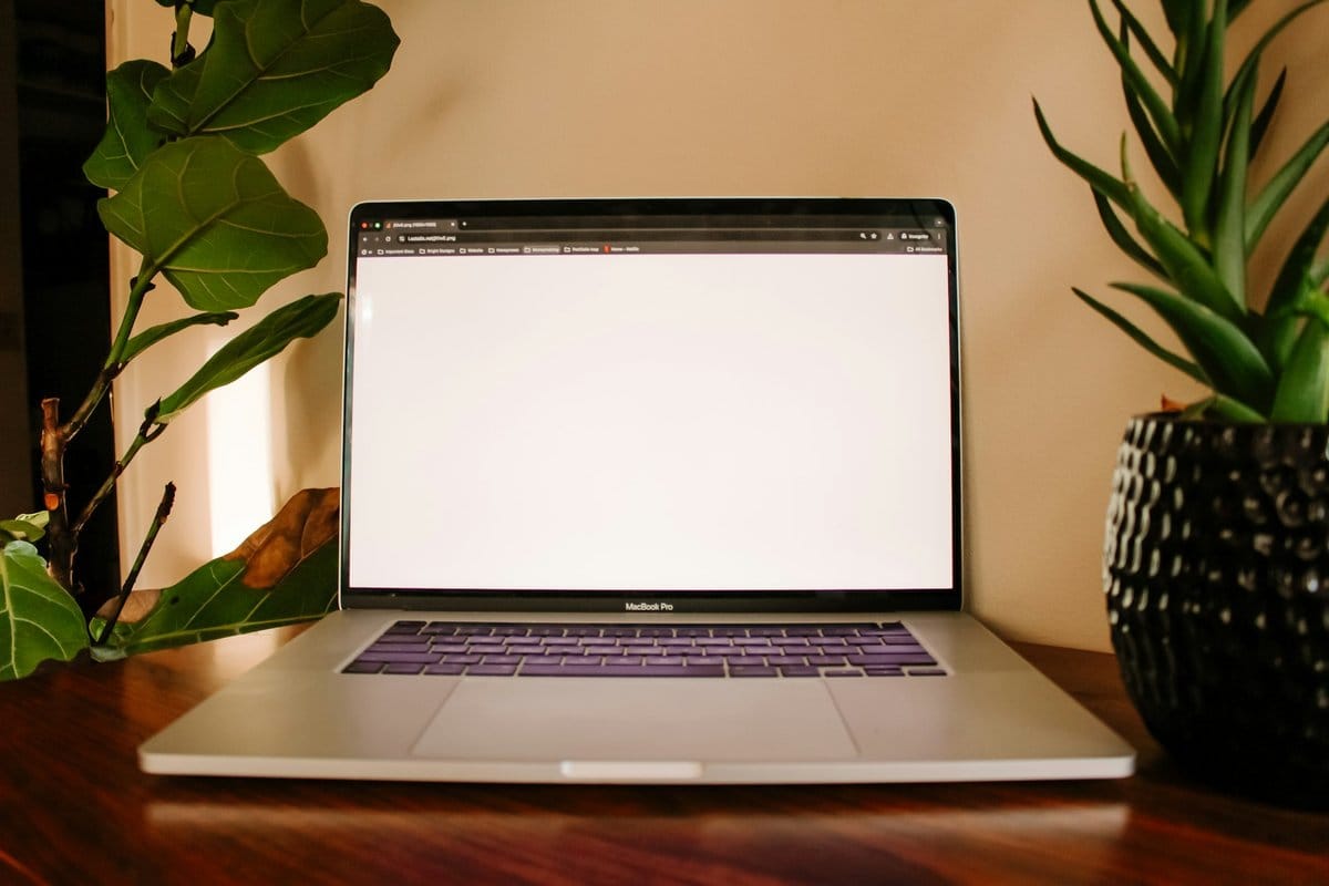 Laptop op een houten tafel tussen planten, klaar voor een nieuwe website